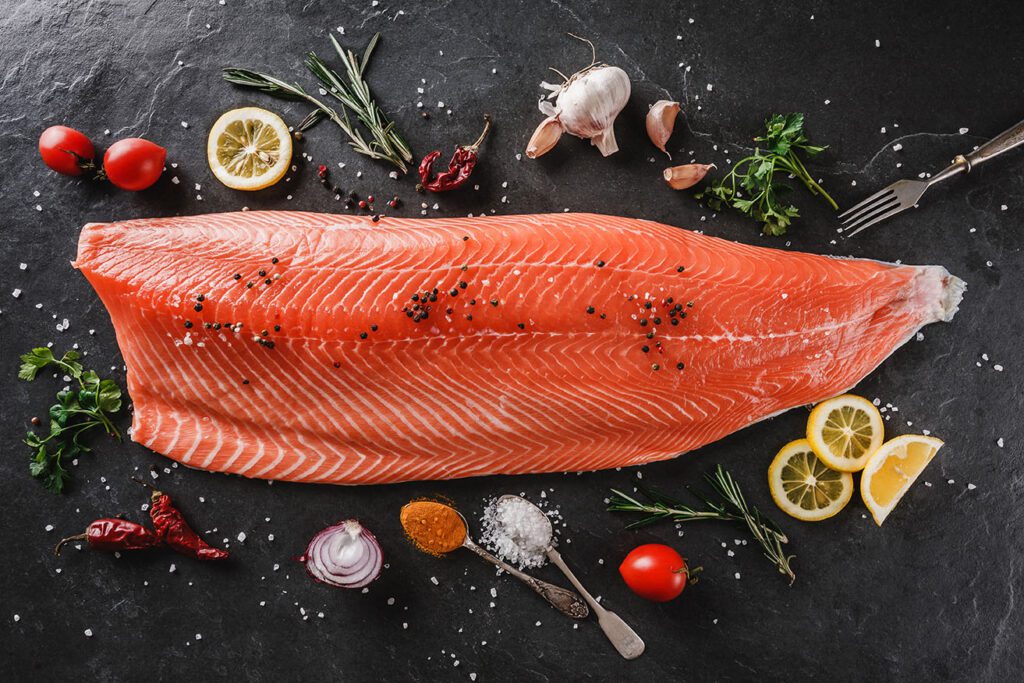 Salmon fillet with herbs on a black stone background