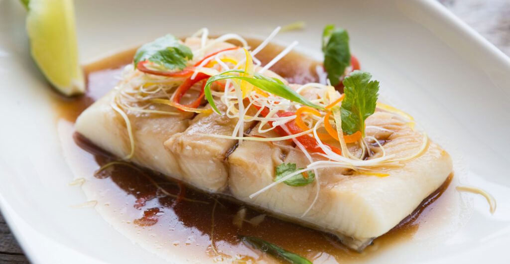 Cooked white fish with julienne vegetables and sauce