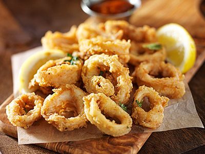 Fried calamari with lemons on a wooden background